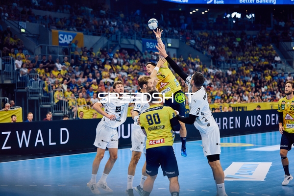 Ein Spieler von Rhein Neckar Löwen springt, um einen Wurf zu machen, während Spieler von THW Kiel versuchen zu blocken.