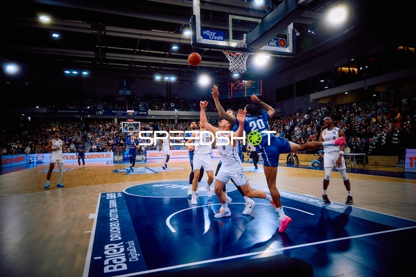 Ein Spieler von MLP Academics Heidelberg versucht, einen Korb zu werfen, während ein Spieler der Brose Bamberg verteidigt.