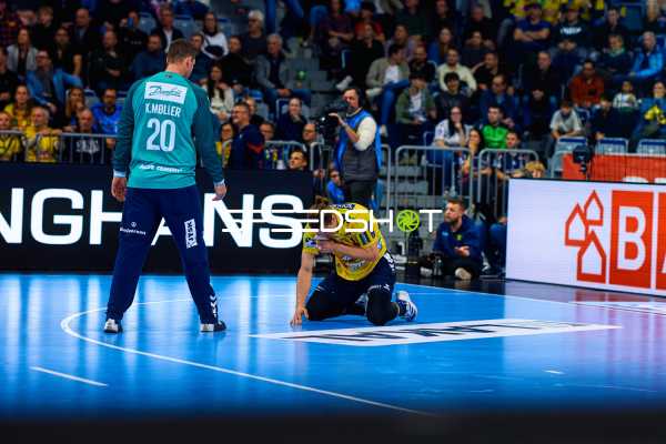 Ein Spieler der Rhein Neckar Löwen kniet auf dem Boden, während ein Spieler der SG Flensburg Handewitt daneben steht.