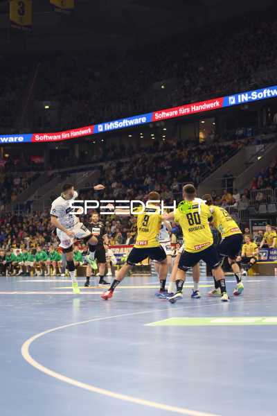 Ein Spieler von HSG Wetzlar springt in die Luft, während Spieler der Rhein Neckar Löwen verteidigen.