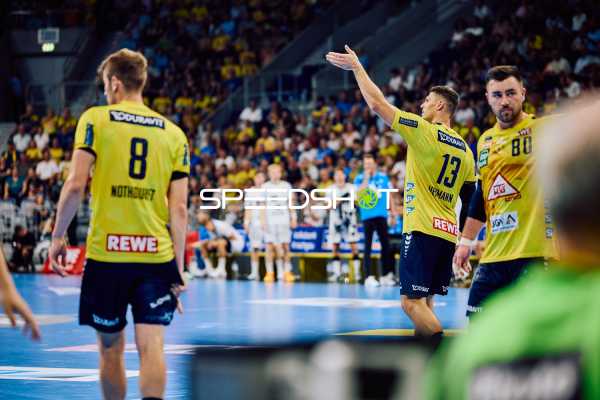 Ein Spieler der Rhein Neckar Löwen signalisiert eine Aktion, während die anderen Spieler aufmerksam sind.