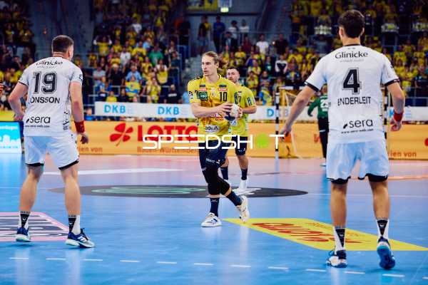 Ein Spieler von Rhein Neckar Löwen bereitet sich darauf vor, den Ball zu passen, während zwei Spieler von MT Melsungen ihn verteidigen.
