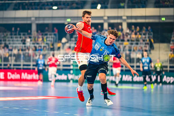 Ein Spieler der Rhein-Neckar Löwen versucht, einen Spieler von Benfica Lissabon im Sprung zu blockieren.