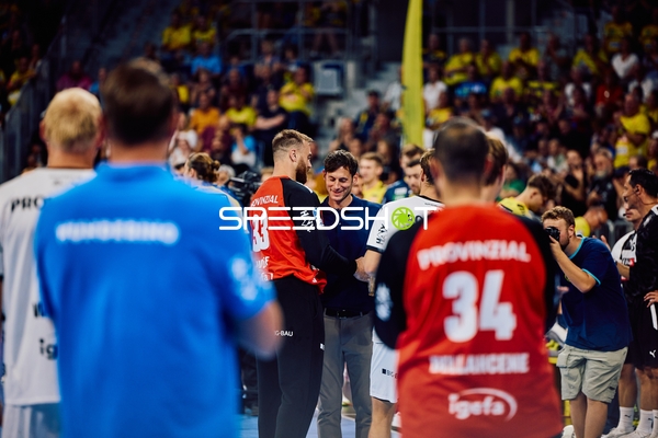 Spieler von Rhein-Neckar Löwen und THW Kiel stehen zusammen auf dem Spielfeld.