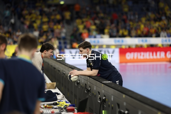 Ein Spieler lehnt sich über die Bande und spricht mit jemandem am Spielfeldrand.