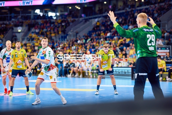 Ein Spieler des SC Magdeburg bereitet sich darauf vor, den Ball im Angriffsspiel zu passen, während der Torwart der Rhein Neckar Löwen sich darauf einstellt.