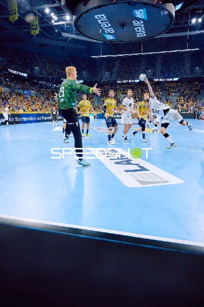 Ein Spieler von THW Kiel springt zum Torwurf während ein Torwart von Rhein Neckar Löwen versucht, den Ball zu blocken.