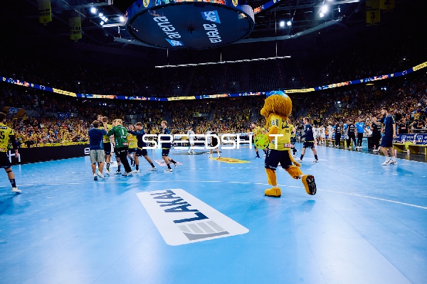 Die Spieler und das Maskottchen der Rhein Neckar Löwen feiern auf dem Spielfeld.