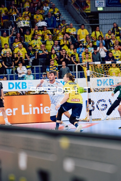 Ein Spieler von HSV Hamburg versucht, den Ball Richtung Tor zu werfen, während ein Spieler der Rhein Neckar Löwen verteidigt.