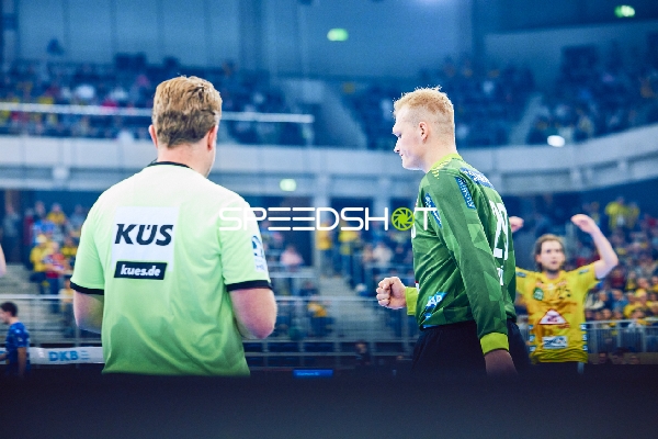 Ein Spieler der Rhein Neckar Löwen läuft auf dem Spielfeld, während ein Schiedsrichter zu sehen ist.