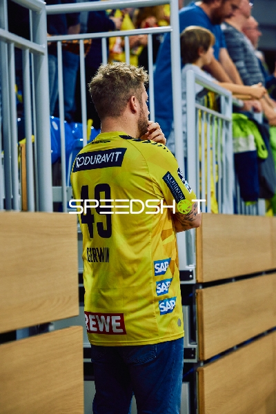 Eine Person mit einem Rhein Neckar Löwen Trikot beobachtet das Spiel.