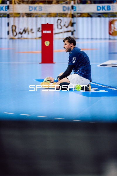 Ein Spieler sitzt mit einem Ball auf dem Spielfeld.