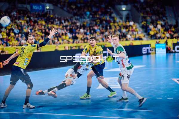 Ein Spieler von FRISCH AUF! Göppingen versucht einen Wurf, während zwei Spieler der Rhein-Neckar Löwen ihn verteidigen.