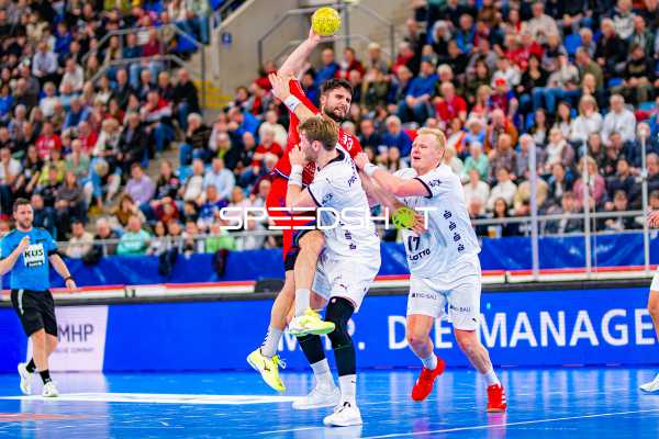 Ein Spieler von SG BBM Bietigheim springt, um ein Tor zu werfen, während er von einem Verteidiger von THW Kiel blockiert wird.