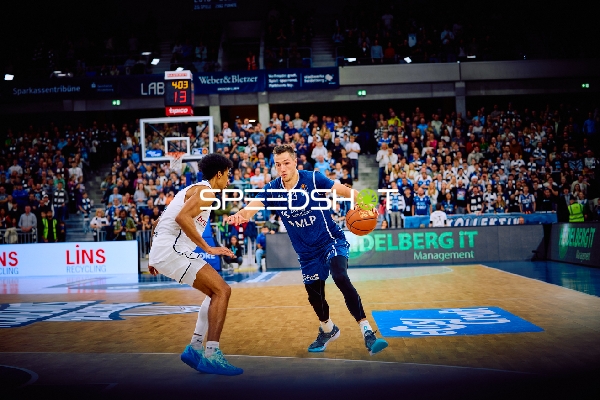 Ryan Mikesell von MLP Academics Heidelberg dribbelt den Ball gegen einen Verteidiger von Brose Bamberg.