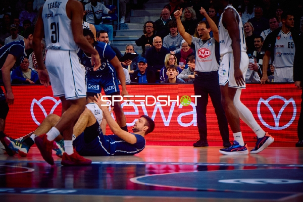 Ein Spieler von Brose Bamberg hilft einem am Boden liegenden Mitspieler auf.