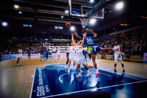 Ein Spieler von Brose Bamberg versucht, einen Korbleger zu erzielen, während mehrere Spieler von MLP Academics Heidelberg verteidigen.