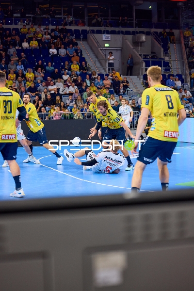 Ein Spieler von THW Kiel liegt am Boden, während mehrere Spieler von Rhein Neckar Löwen versuchen, den Ball zu sichern.