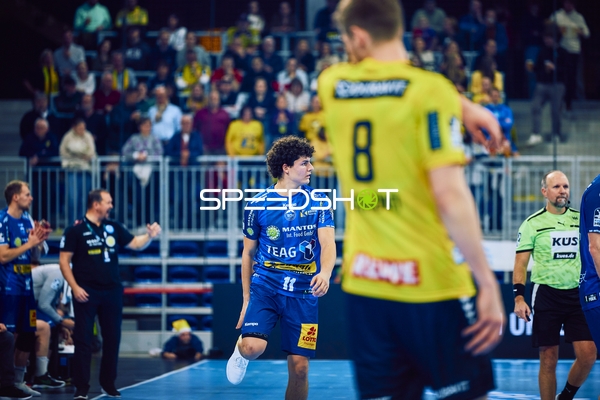 Ein Spieler von ThSV Eisenach läuft auf das Spielfeld, während ein Spieler von Rhein Neckar Löwen im Vordergrund sichtbar ist.