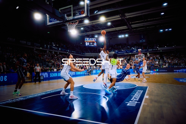 Ein Spieler der MLP Academics Heidelberg springt zum Korbwurf, während ein Spieler von Brose Bamberg versucht zu blocken.