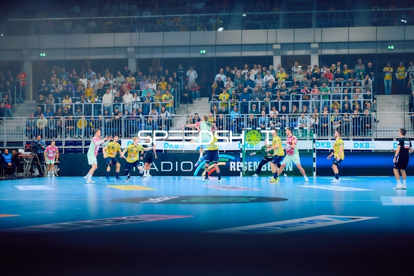 Ein Spieler von Rhein Neckar Löwen springt zum Wurf, während die Verteidiger von Füchse Berlin versuchen, den Angriff zu blocken.