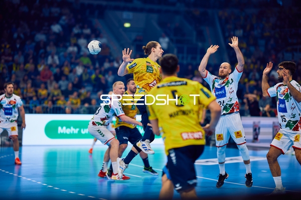 Ein Spieler der Rhein Neckar Löwen versucht einen Wurf, während mehrere Spieler von SC Magdeburg verteidigen.