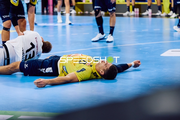 Ein Spieler der Rhein Neckar Löwen liegt auf dem Boden, während ein Spieler von HSV Hamburg in seiner Nähe ist.