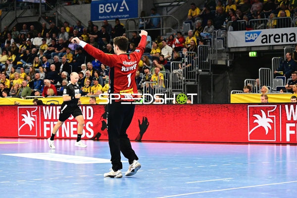 Handballspieler mit erhobenen Armen vor Schiedsrichter