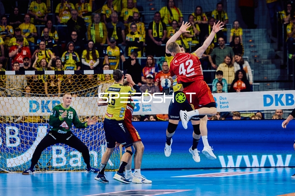 Ein Spieler des TSV Hannover Burgdorf springt zum Wurf, während Spieler der Rhein-Neckar Löwen verteidigen.