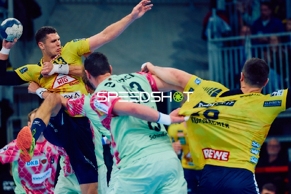 Ein Spieler der Rhein Neckar Löwen springt mit dem Ball in der Hand, während ein Spieler der Füchse Berlin versucht, ihn zu blocken.