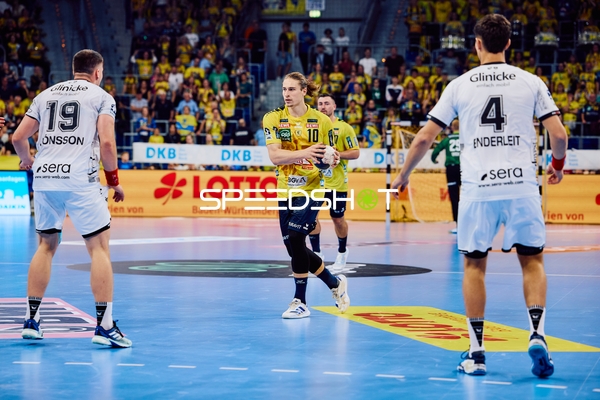 Ein Spieler von Rhein Neckar Löwen bereitet sich darauf vor, den Ball zu passen, während zwei Spieler von MT Melsungen ihn verteidigen.