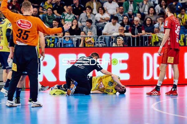 Ein Spieler der Rhein Neckar Löwen liegt verletzt auf dem Boden, während ein Teammitglied ihm hilft.