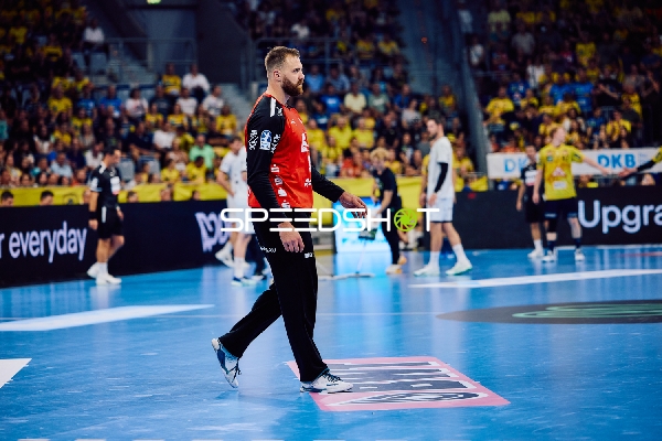 Ein Spieler in einem roten Trikot steht auf dem Spielfeld.