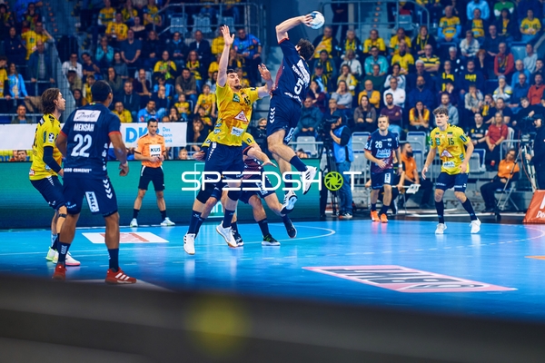 Ein Spieler von SG Flensburg Handewitt springt, um einen Wurf aufs Tor zu machen, während die Verteidigung von Rhein Neckar Löwen versucht zu blocken.