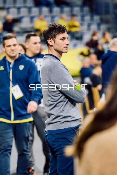 Ein Trainer steht mit verschränkten Armen am Spielfeldrand.