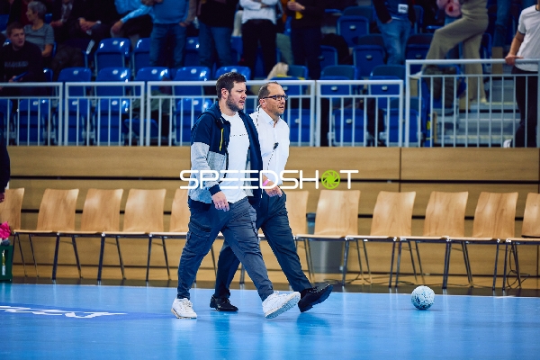 Zwei Männer gehen über das Spielfeld.