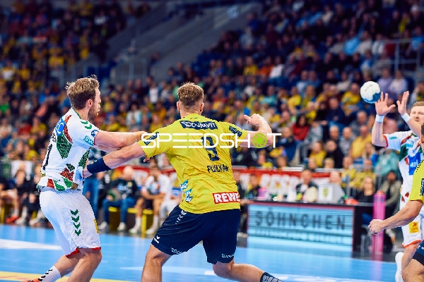 Ein Spieler der Rhein Neckar Löwen versucht, einen Wurf gegen die Verteidigung des SC Magdeburg zu machen.