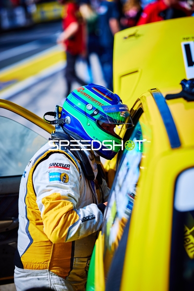 Rennfahrer neben Fahrzeug in Boxengasse