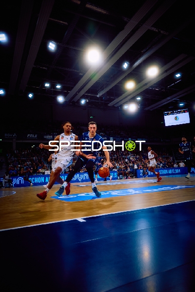 Ein Spieler von MLP Academics dribbelt den Ball, während ein Spieler von Brose Bamberg verteidigt.