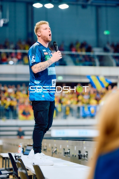 Eine Person singt oder spricht in ein Mikrofon auf einem Tisch.