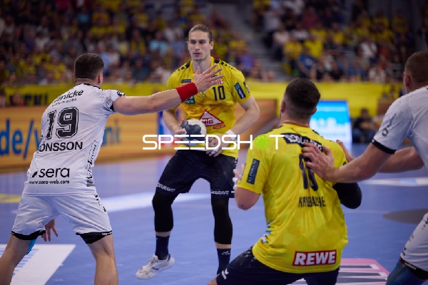 Ein Spieler von Rhein Neckar Löwen bereitet sich darauf vor, den Ball zu passen, während er von einem Spieler von SC Magdeburg verteidigt wird.