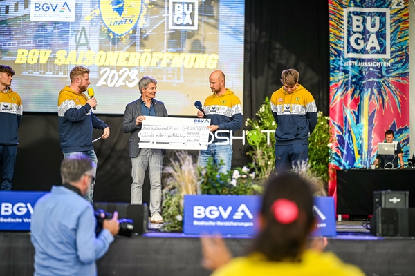 Übergabe eines großen Schecks auf der Bühne während der Saisoneröffnung.