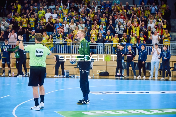 Spieler auf dem Spielfeld mit jubelnden Fans