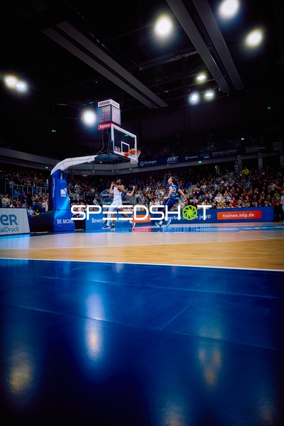 Ein Spieler von Heidelberg springt zum Korb für einen Layup, während ein Spieler von Brose Bamberg verteidigt.
