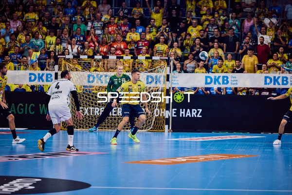 Ein Spieler von Rhein Neckar Löwen versucht, an einem gegnerischen Verteidiger vorbeizukommen, während der Torwart in Position ist.