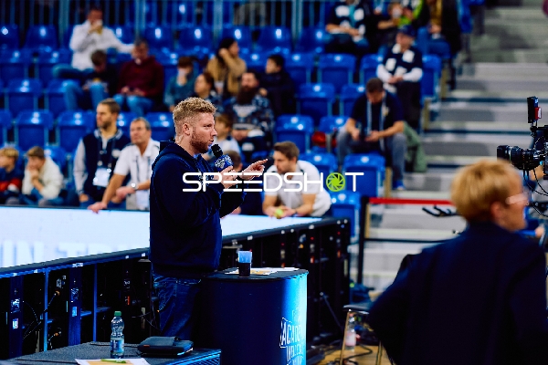 Ein Moderator spricht vor dem Publikum in einer Sportarena.