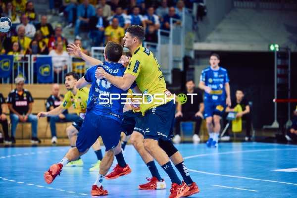 Ein Spieler der Rhein Neckar Löwen im gelben Trikot versucht, einen Spieler von ThSV Eisenach zu blockieren.