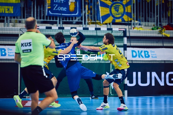 Ein Spieler von ThSV Eisenach greift mit dem Ball an und wird von zwei Spielern der Rhein Neckar Löwen verteidigt.