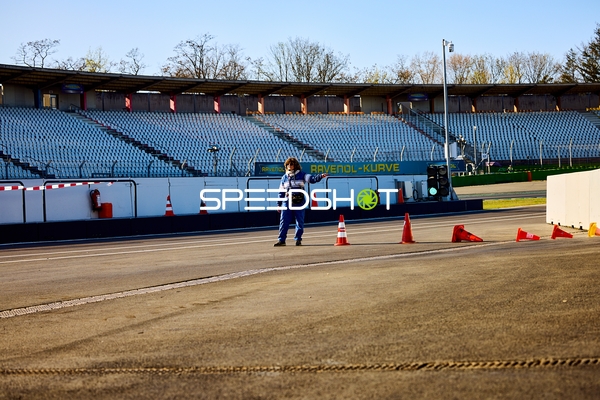 Person in Blau auf der Rennstrecke neben Verkehrskegeln
