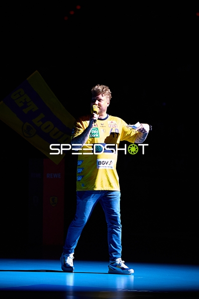 Person spricht in Mikrofon auf dem Spielfeld